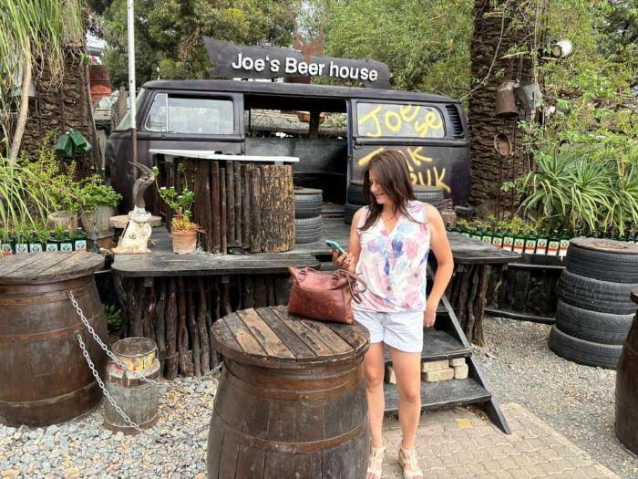 A lady standing in front of a sign for local restaurant Joe's Beer House