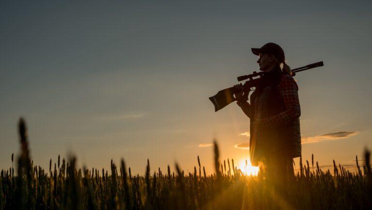 Female hunter holding rifle at sunrise during African hunting trip