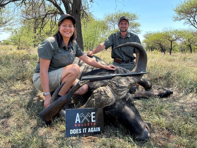 Woman and man posing with Cape buffalo game hunting trophy