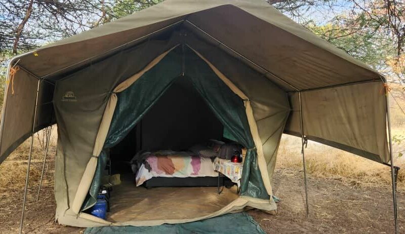 An open tent, showing a bed and side table inside.