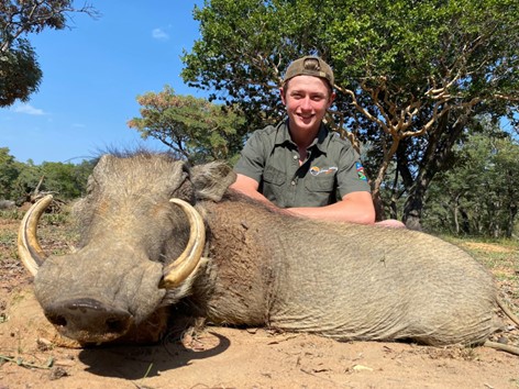 Boy posing with the massive warthog he shot.