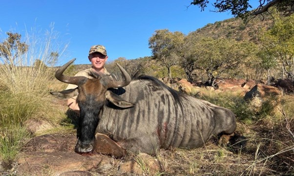 Boy posing with a wildebeest game hunting trophy